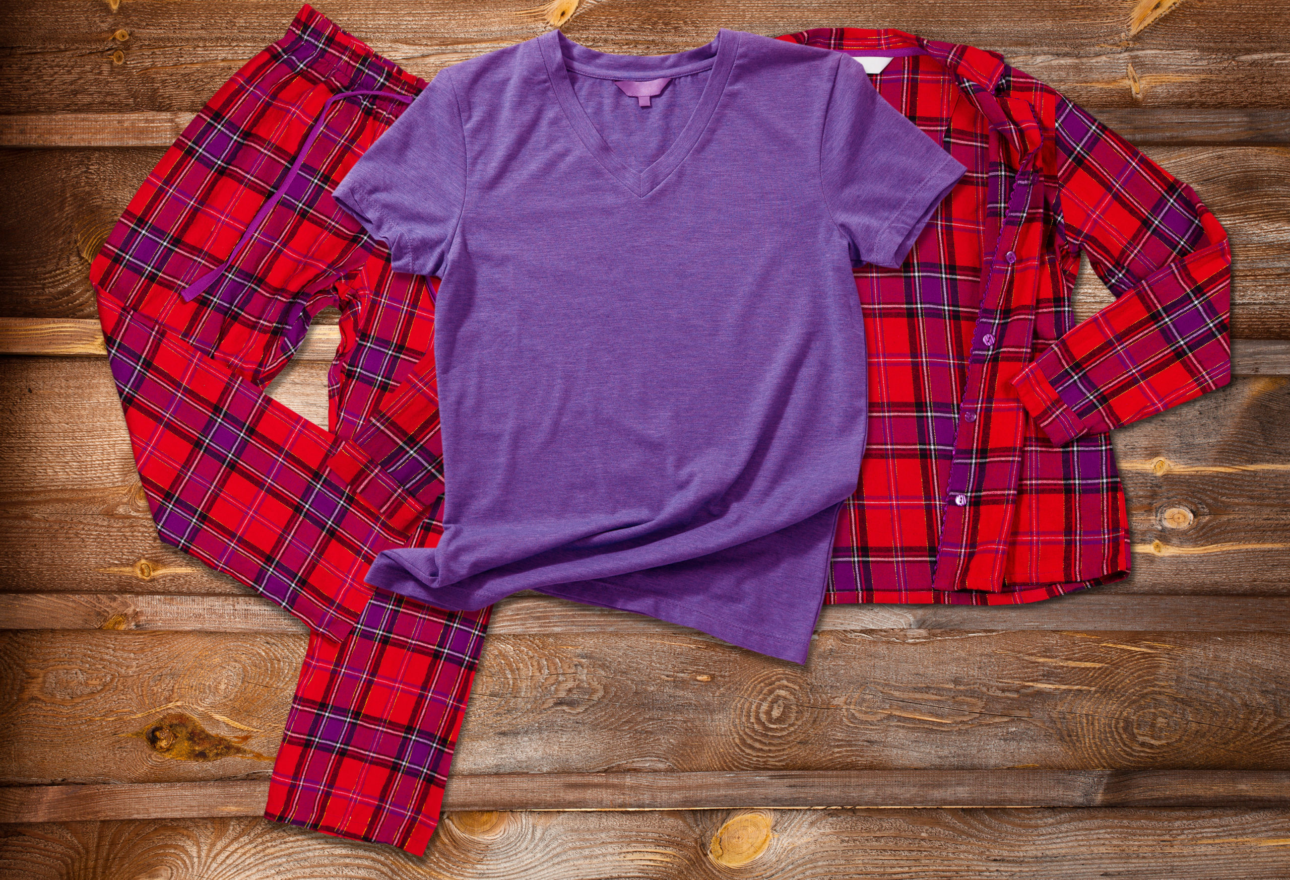 Plaid pajamas and purple shirt laid on wood.