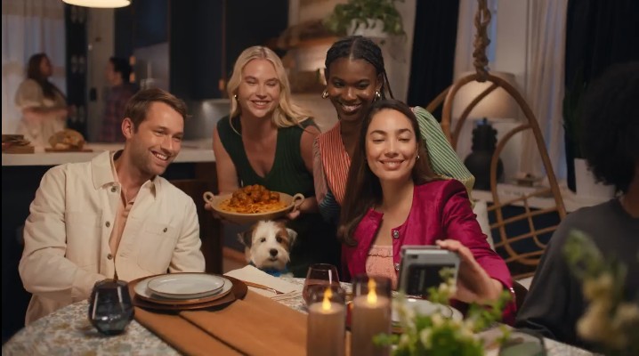 Cotton, The Fabric Of Our Lives, Debuts New Jingle Versions, Expanding Reach - Image of 4 friends sitting around candlelit table with a dog between them posing for a pictures